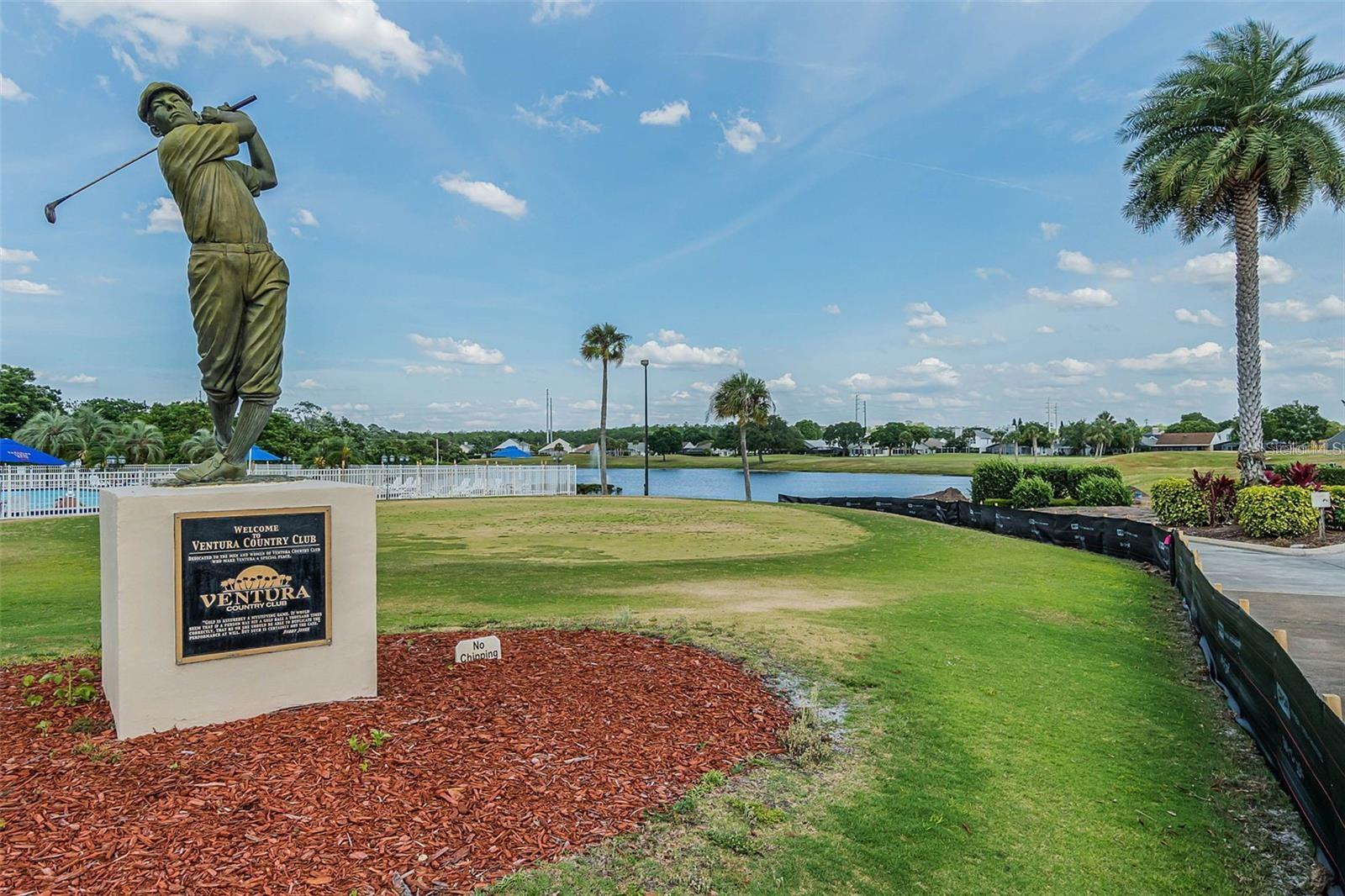 Ventura Country Club entrance with a golfer statue, lake, and palm trees.