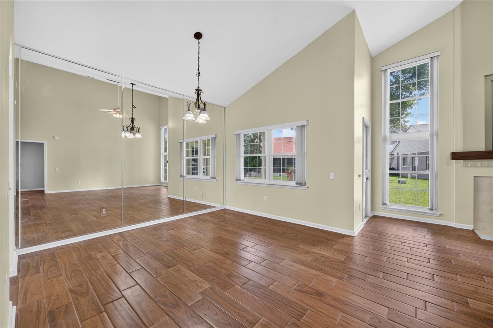 Vacant bedroom with mirrored closet doors, vaulted ceiling, wood-look tile floors, and a fireplace.