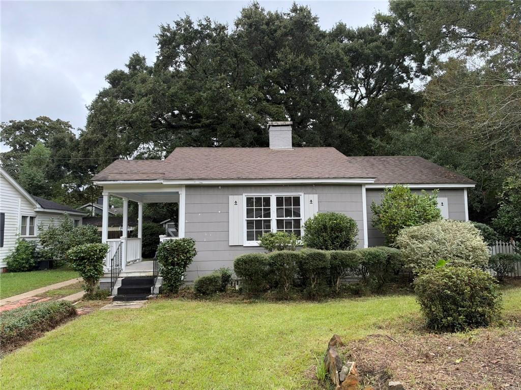 Gray single-story house with a covered porch, white trim, and landscaped front yard.