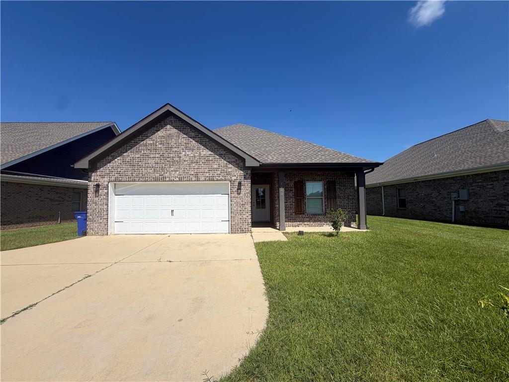 Brick house with a double garage, wide concrete driveway, and green front lawn.