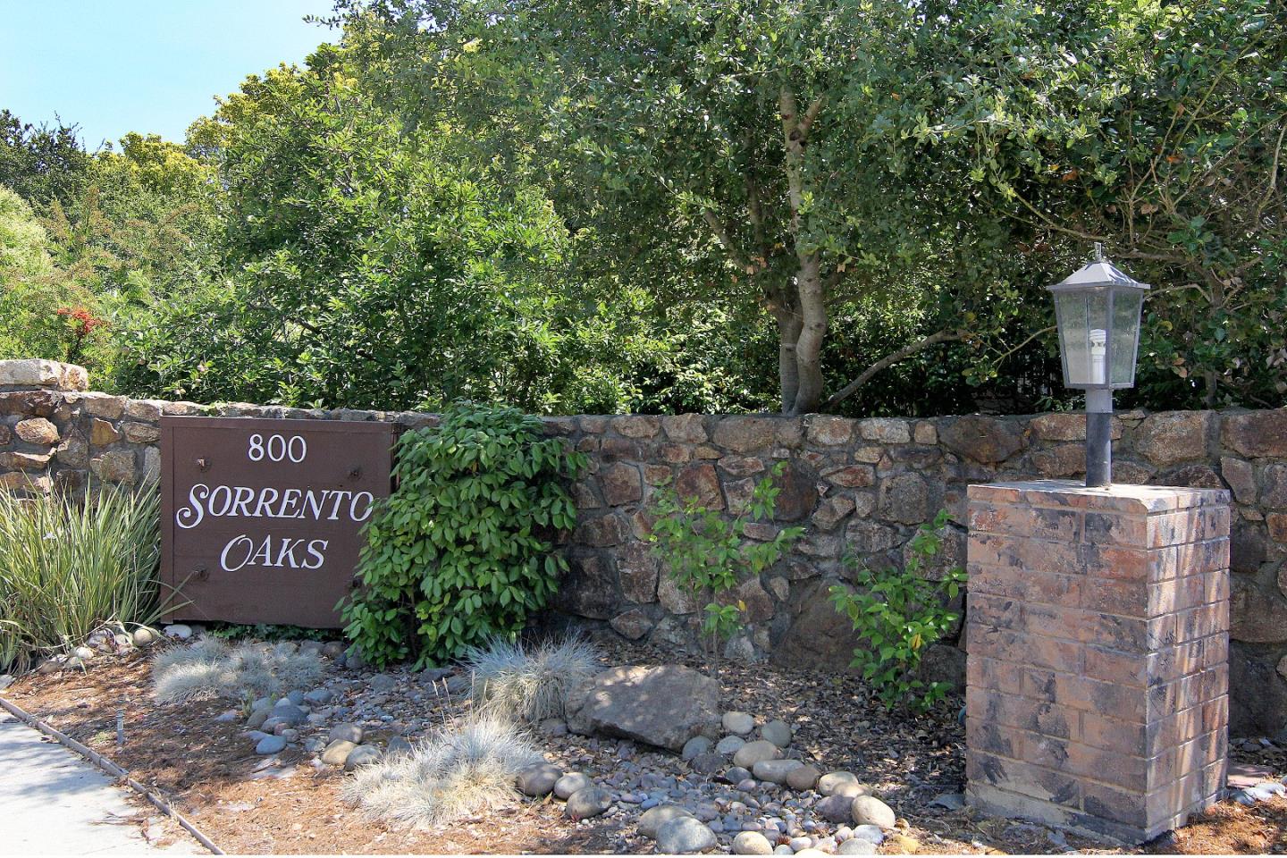 Sorrento Oaks entrance sign beside a stone wall and lantern-topped pillar.
