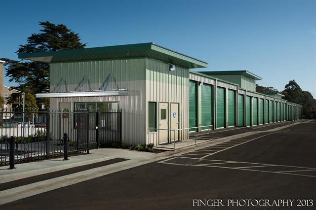 Self-storage facility with green roll-up doors and striped parking spaces.