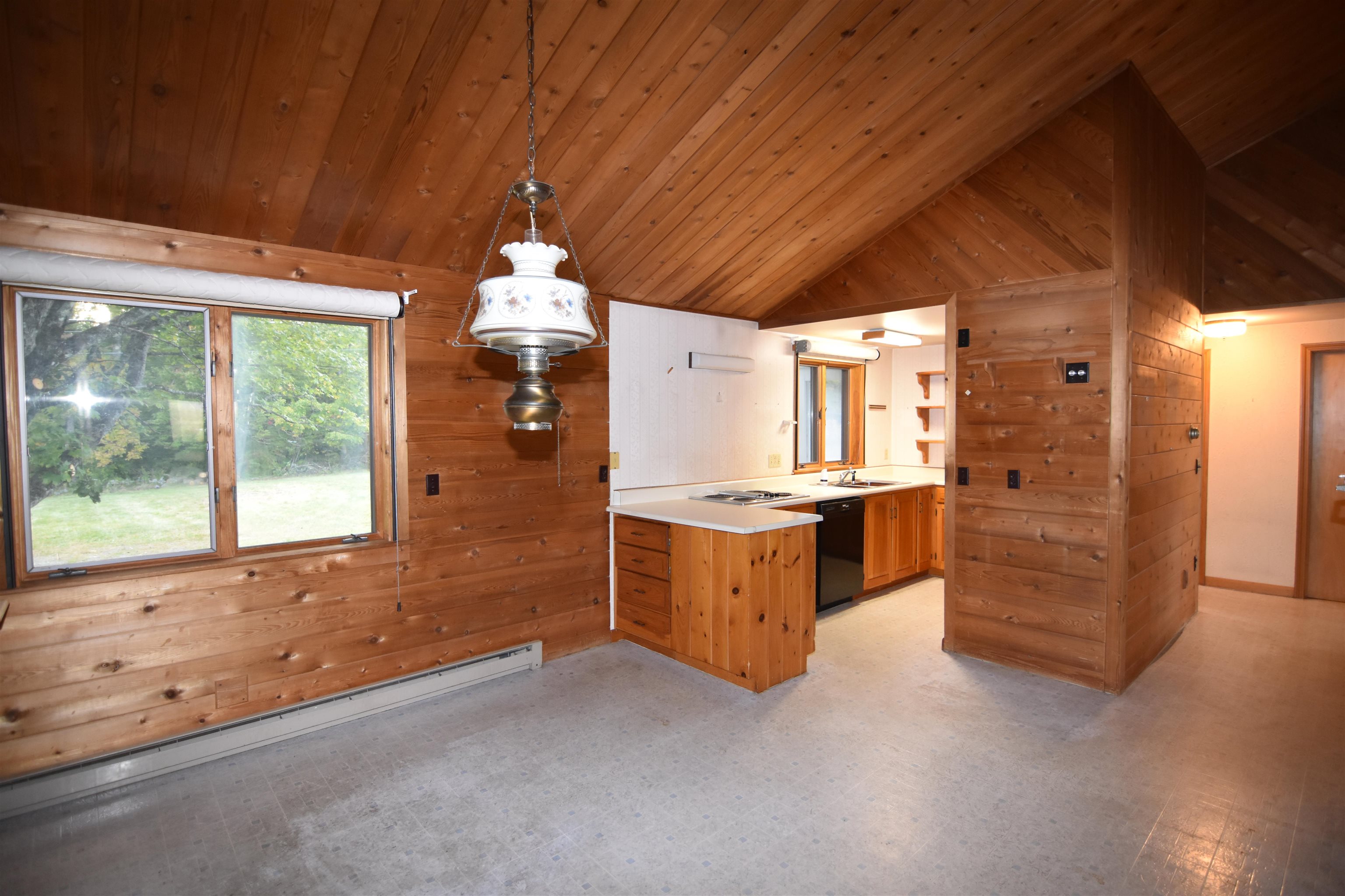 Kitchen with a wood-paneled vaulted ceiling, central island, and large yard-facing window.