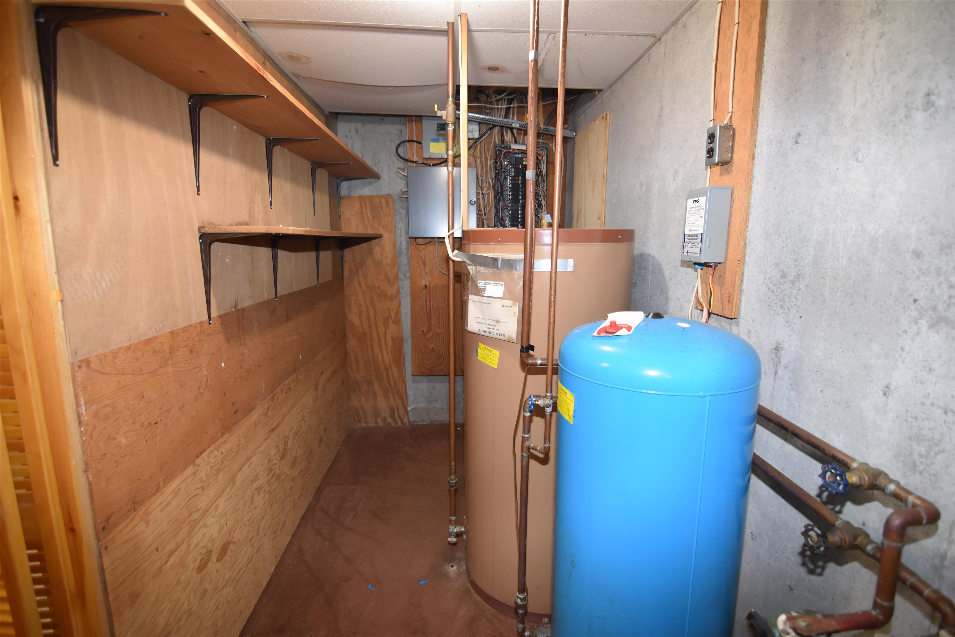 Utility room with plywood shelves, exposed pipes, a water heater, and a blue pressure tank.