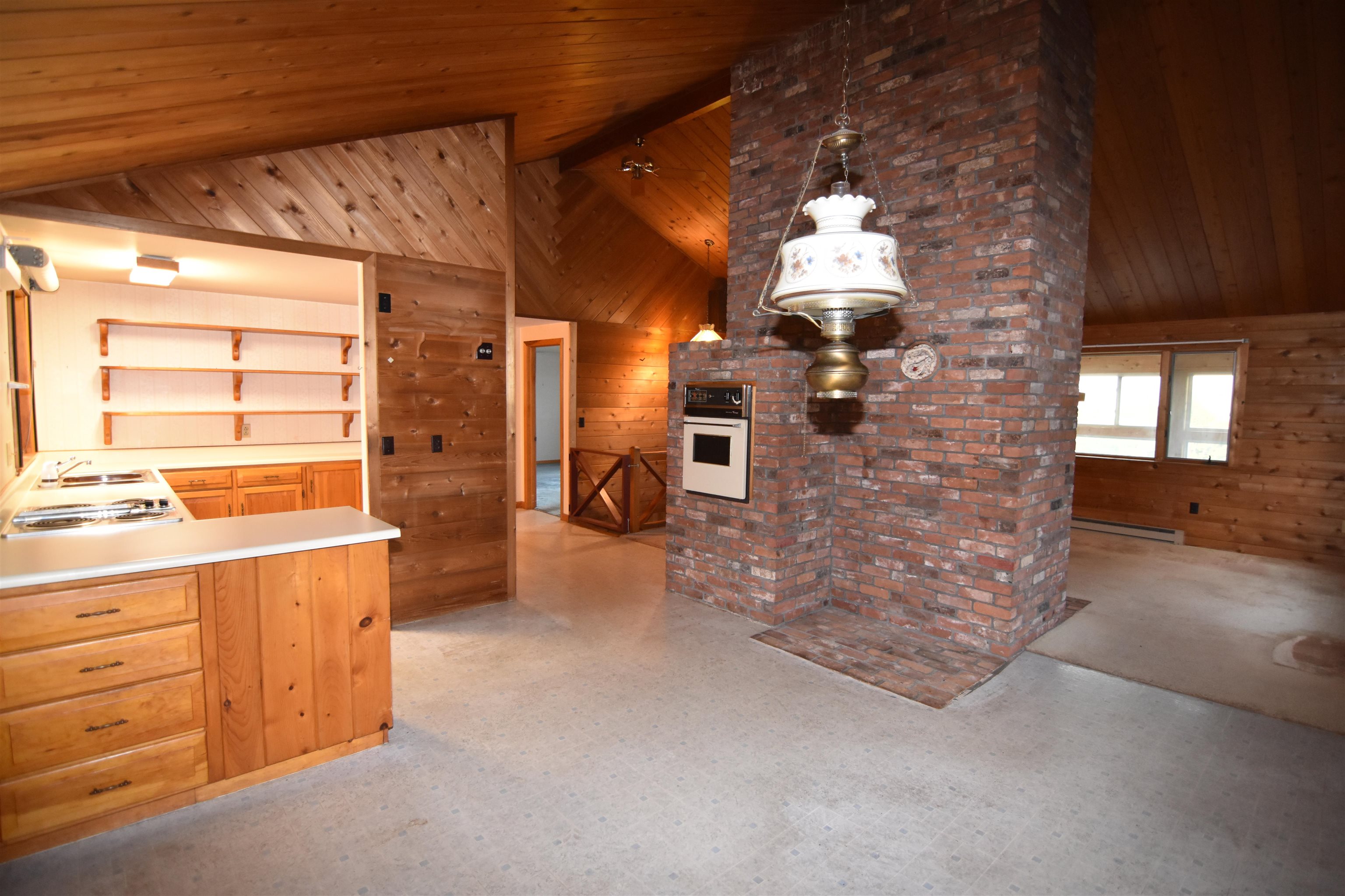 Kitchen with wood cabinetry and a large brick chimney with a built-in oven.