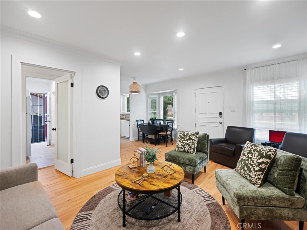 Living room with green seating, a round wood coffee table, and a dining area beyond.