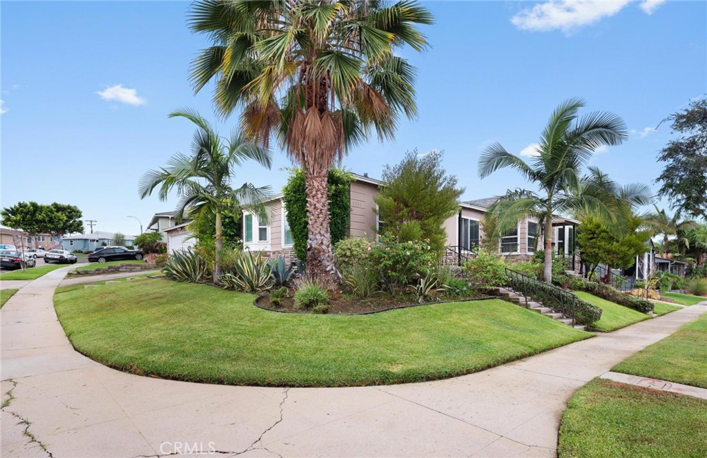 Home on a landscaped corner lot with a broad lawn and several palm trees.