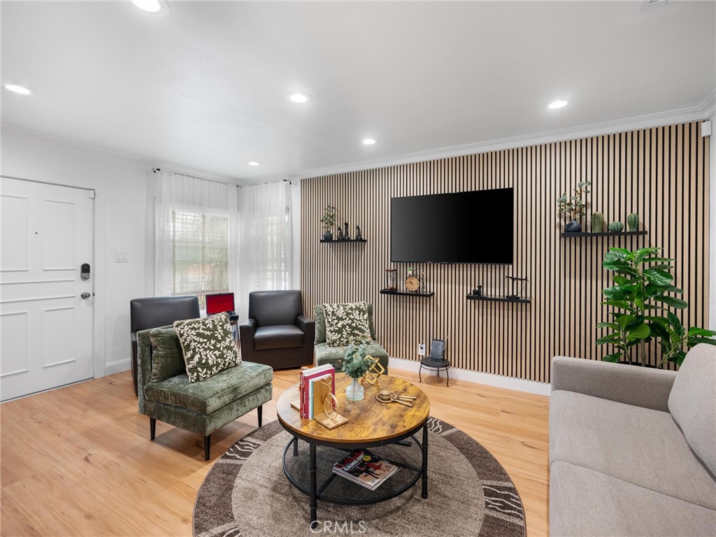 Living room with a slatted wood TV wall, green lounge chairs, and a round coffee table.