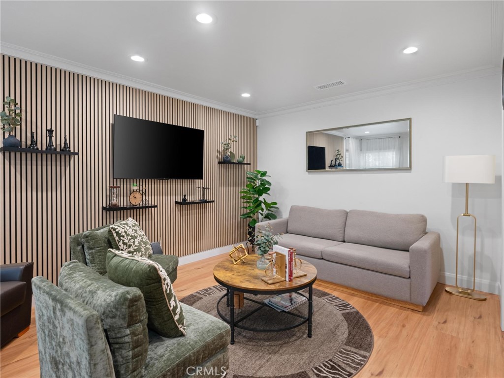 Living room with a slat accent wall, mounted television, gray sofa, and green armchairs.