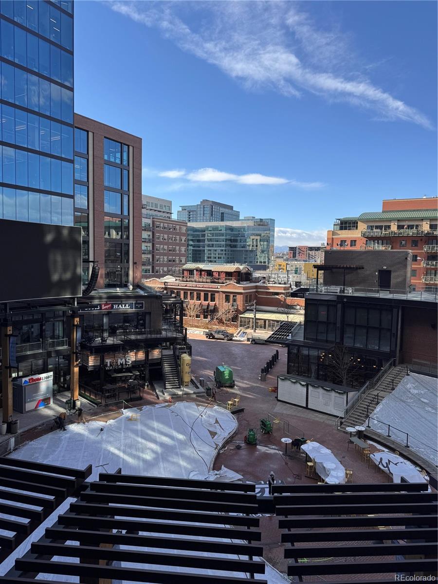 Downtown view over a plaza and surrounding buildings, seen above a black balcony railing.