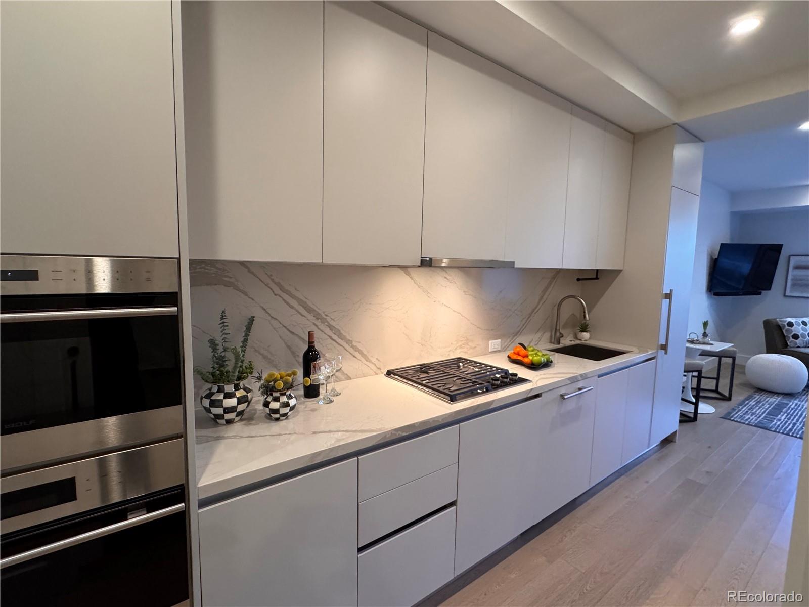 Modern kitchen with white cabinetry, veined stone counters, stainless appliances, and a gas cooktop.