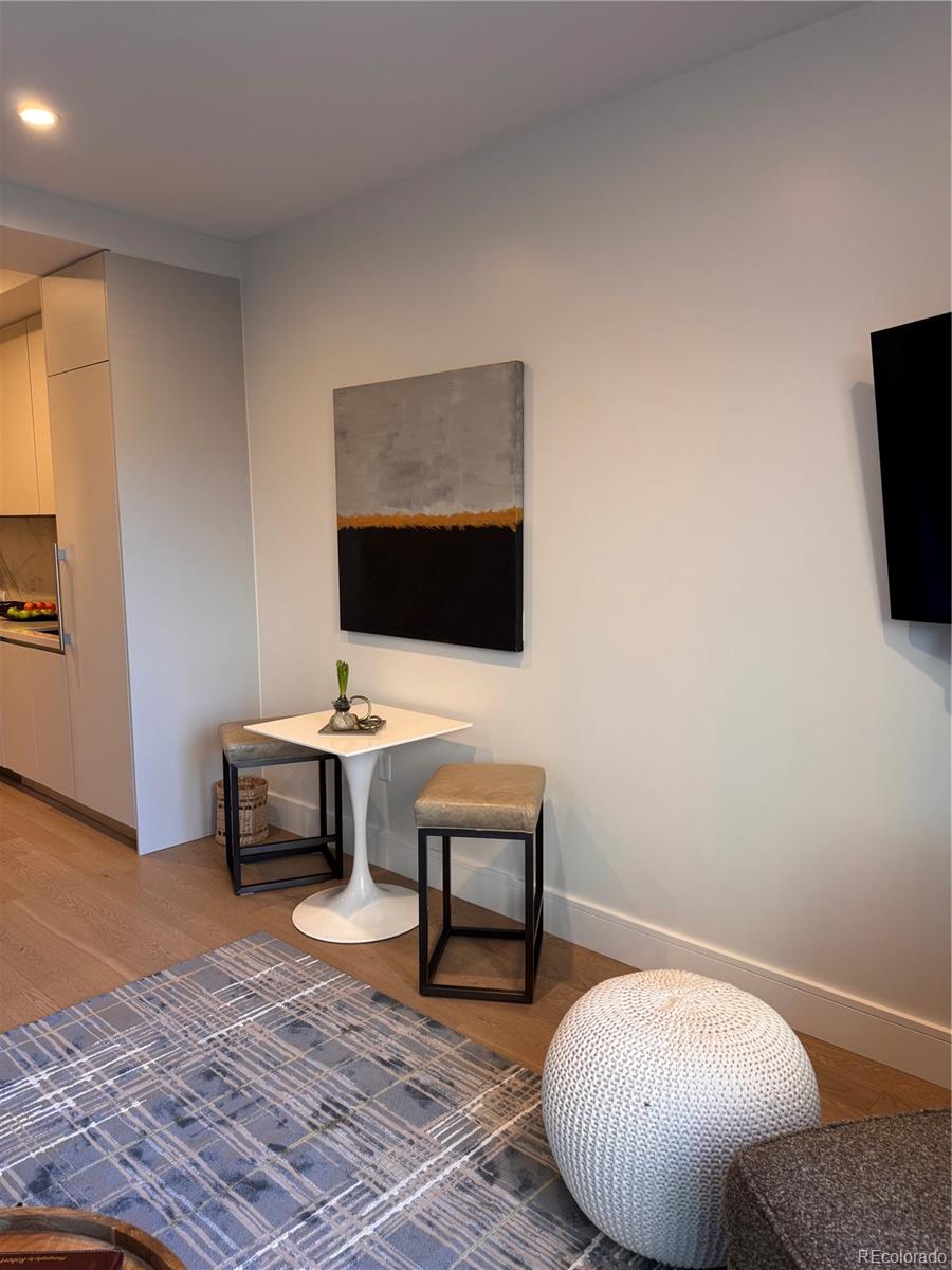 Furnished condo dining nook with a white pedestal table, stools, and abstract wall art.