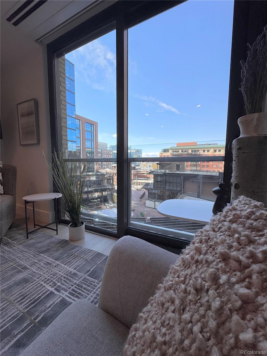 Condo living room with floor-to-ceiling windows overlooking downtown buildings.