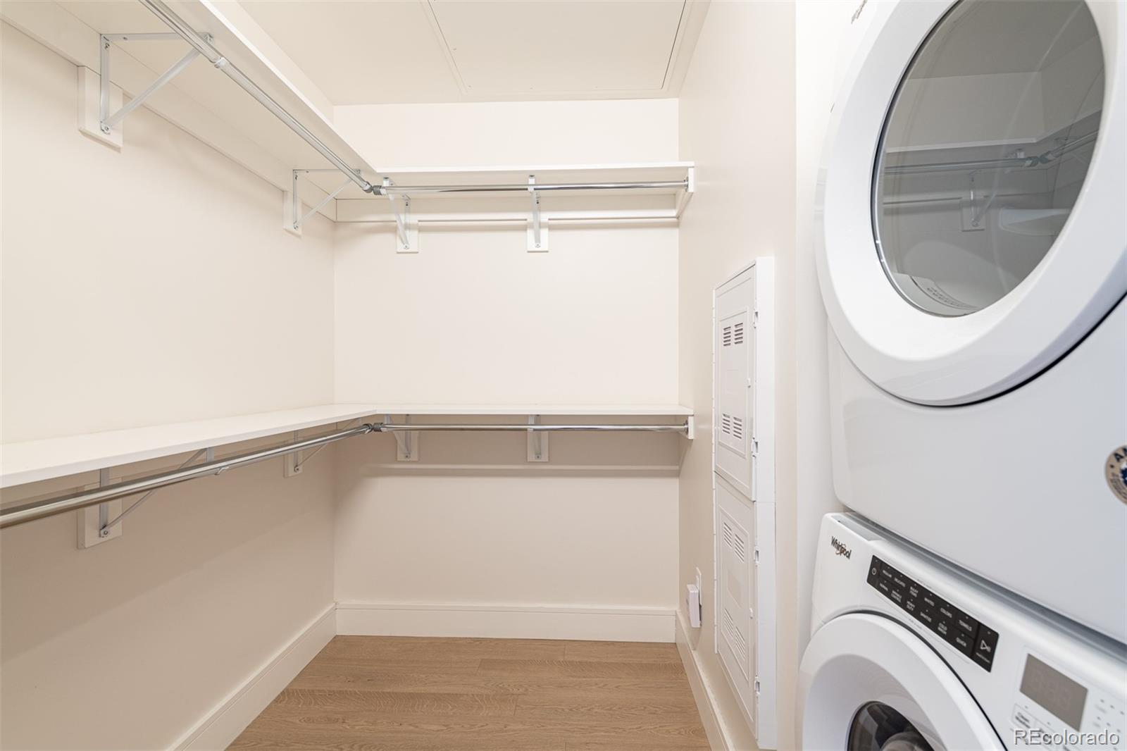 Walk-in closet with wraparound shelving and a stacked washer and dryer.