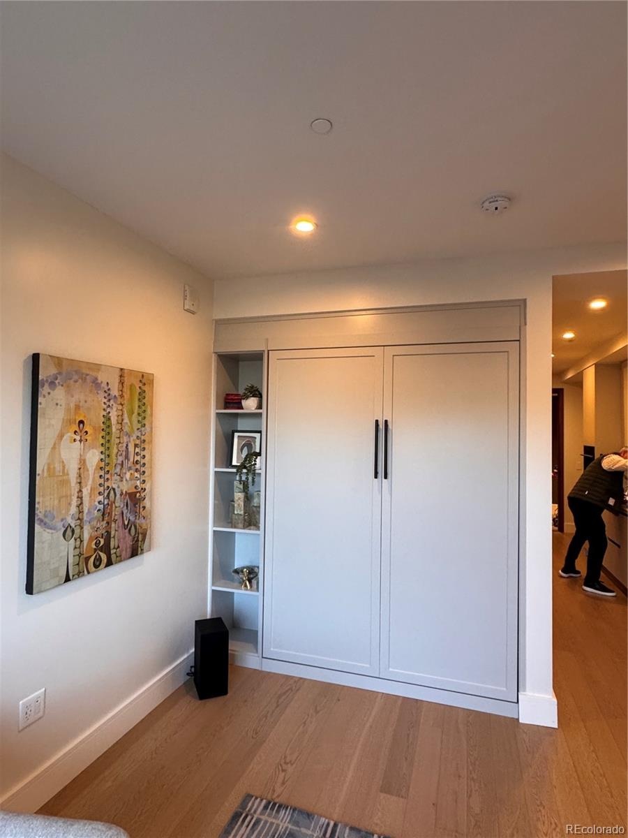 Furnished room with white built-in cabinet, open display shelves, and colorful wall art.