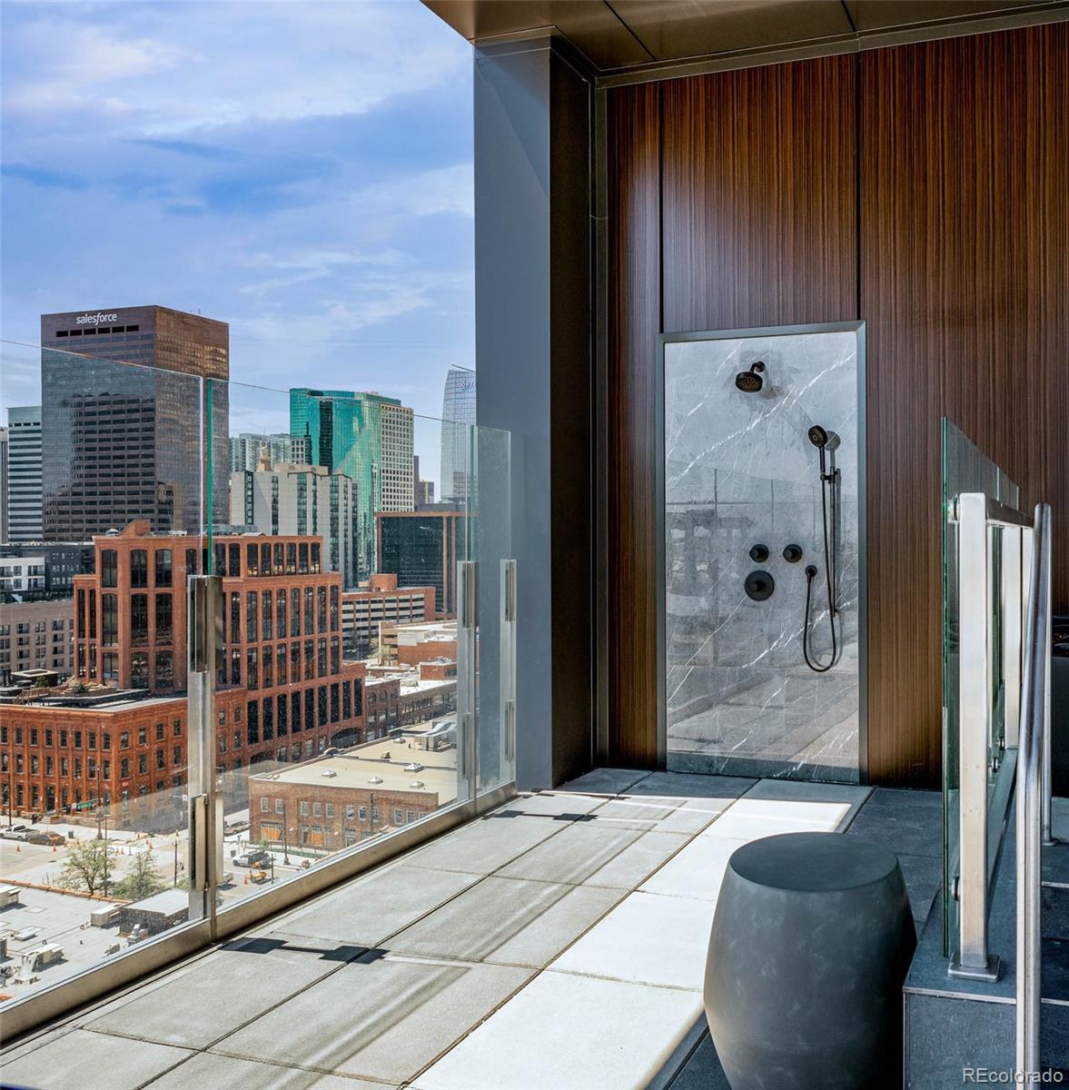 Downtown Denver condo balcony with a marble outdoor shower and city skyline view.