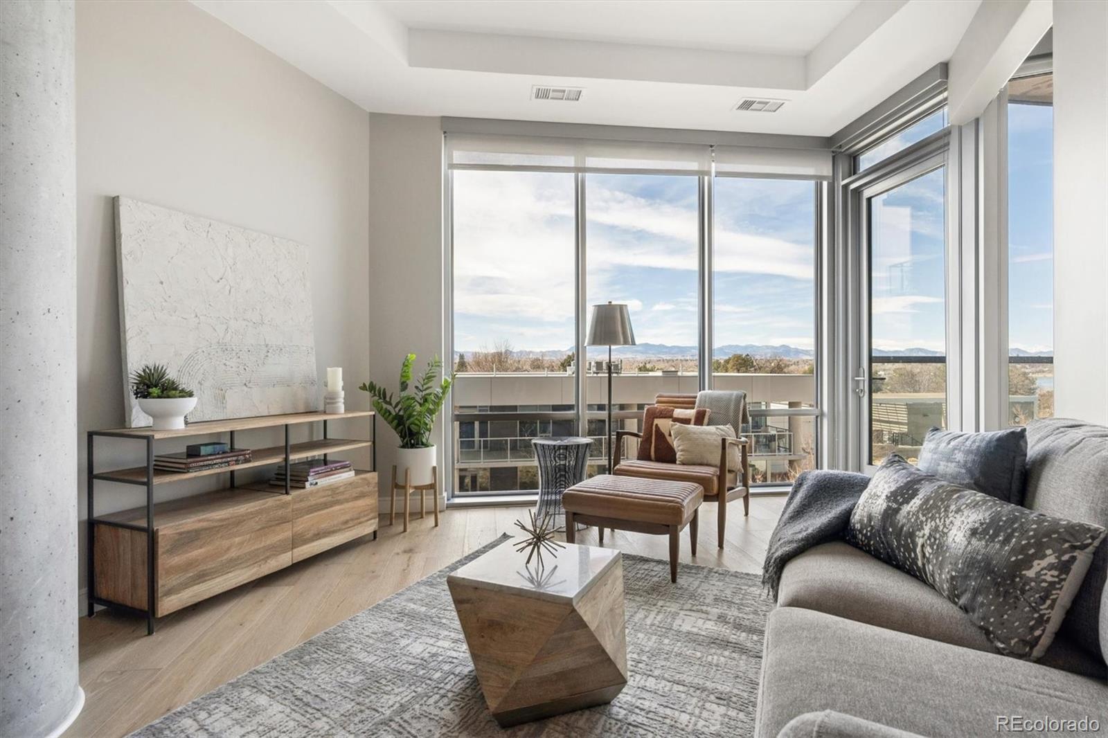 Staged living room with floor-to-ceiling windows and mountain views.