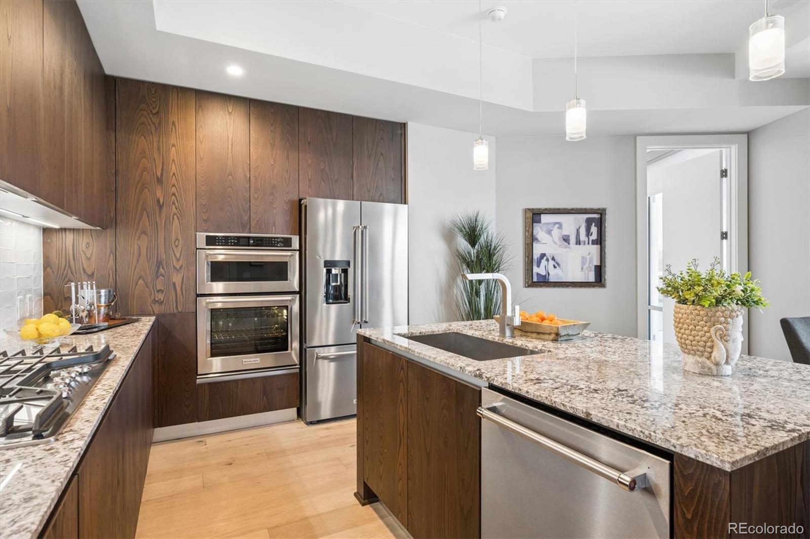 Modern kitchen with walnut cabinets, granite island, and stainless steel appliances.
