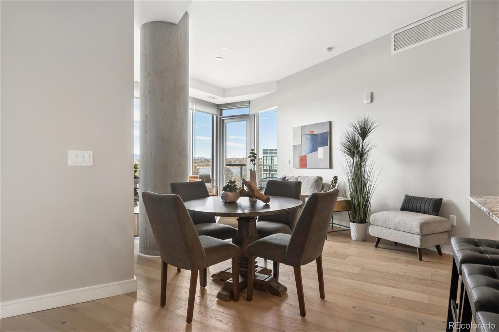 Condo dining area with a round table, concrete column, and corner windows overlooking distant mountains.