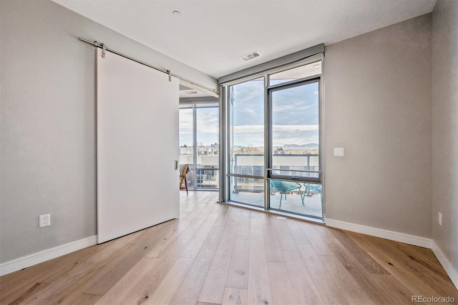 Vacant bedroom with wood flooring and a glass balcony door framing mountain views.