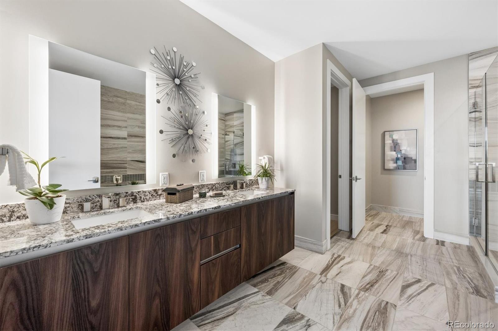 Modern bathroom with a long dark wood vanity, patterned stone counters, and marble-patterned floors.
