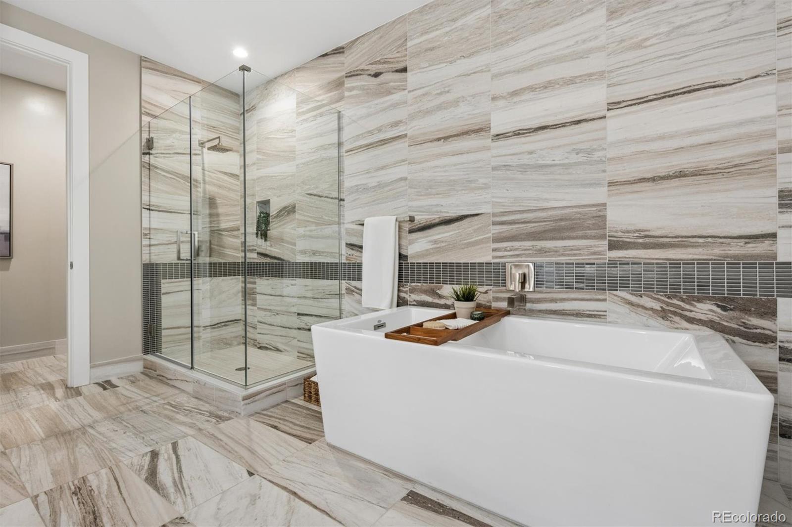 Bathroom with a freestanding tub, glass shower, and dramatic veined stone tile.