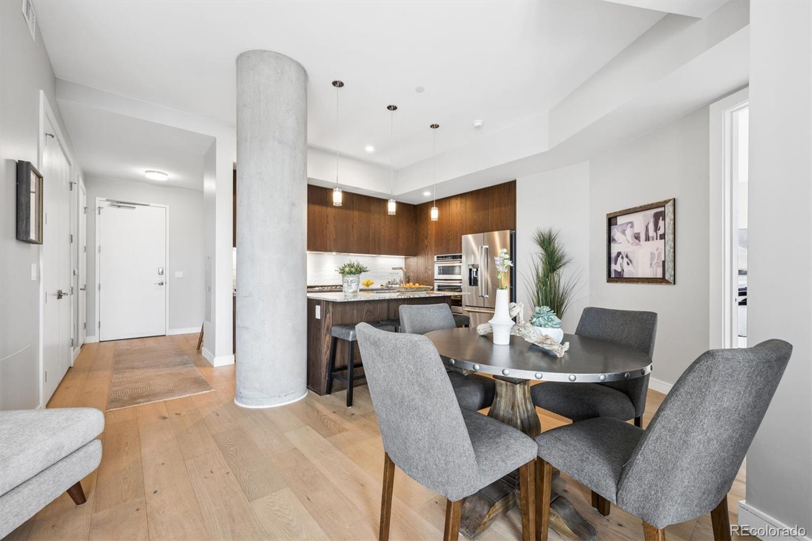 Open-plan condo dining area and kitchen with dark wood cabinetry and a prominent concrete column.