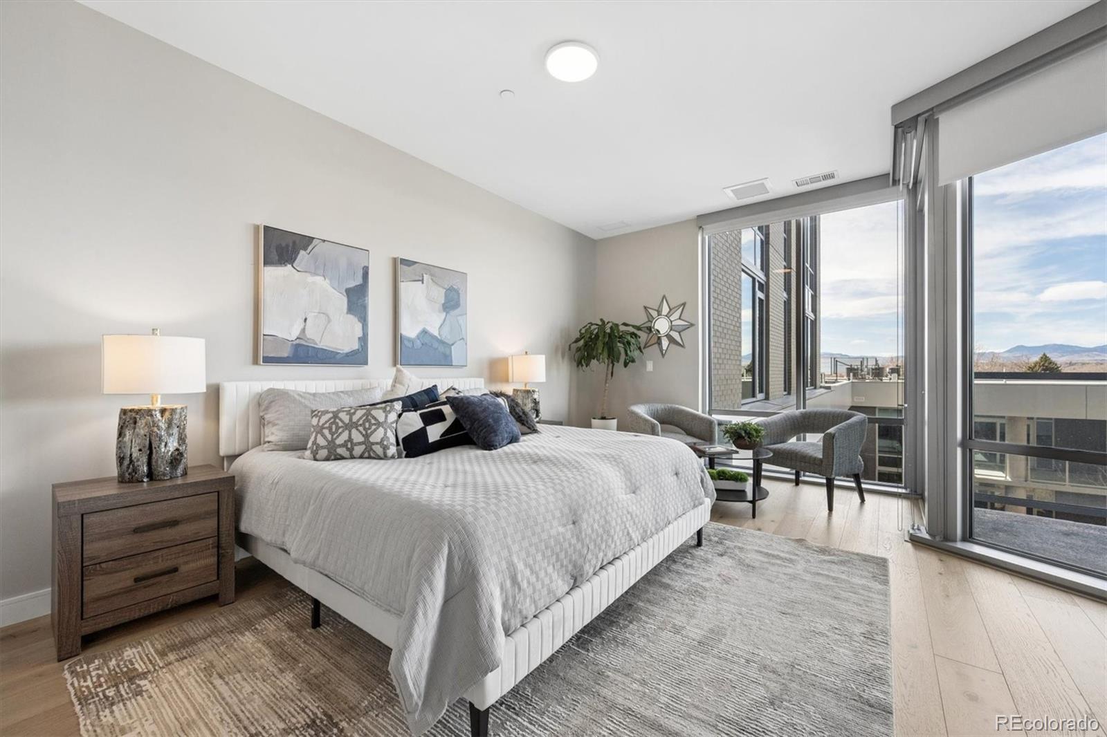 Staged bedroom with a large bed, floor-to-ceiling windows, and distant mountain views.