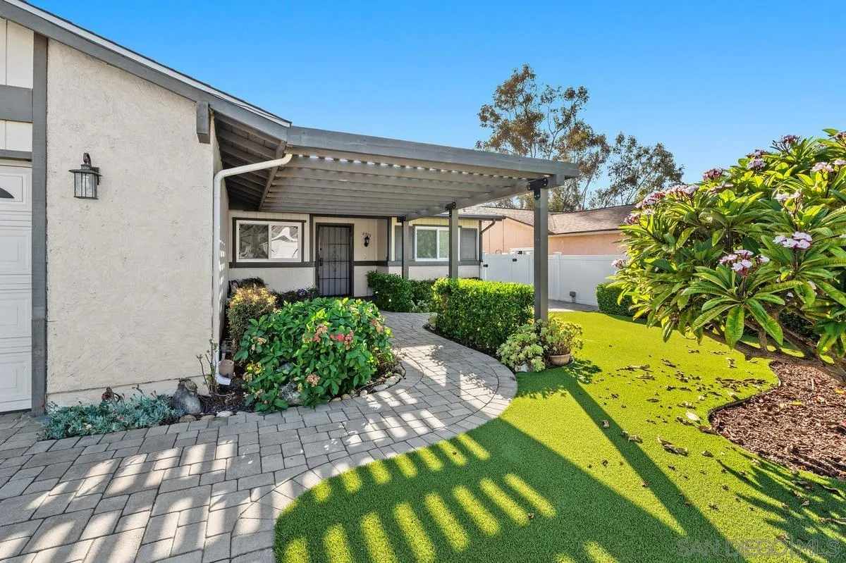 Home exterior with a covered entry, curved paver walkway, and landscaped lawn.