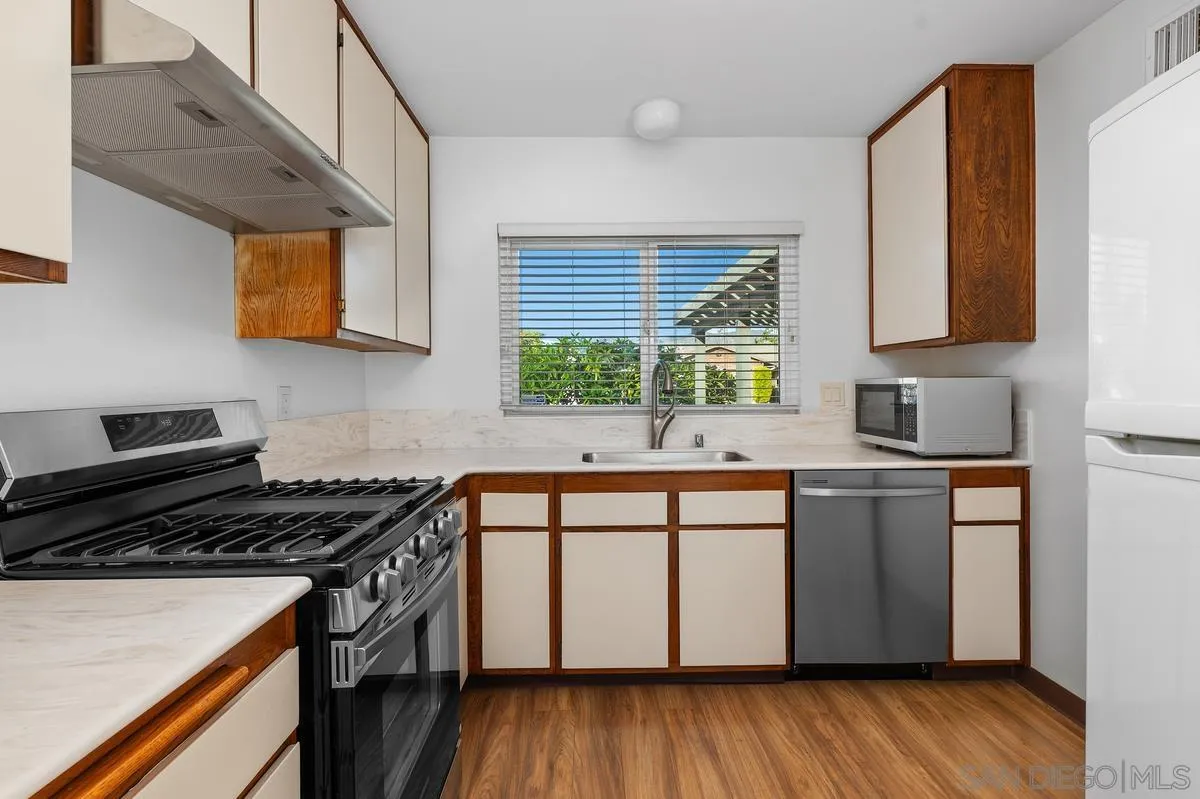 Kitchen with wood-trimmed cream cabinets, stainless appliances, and a window above the sink.