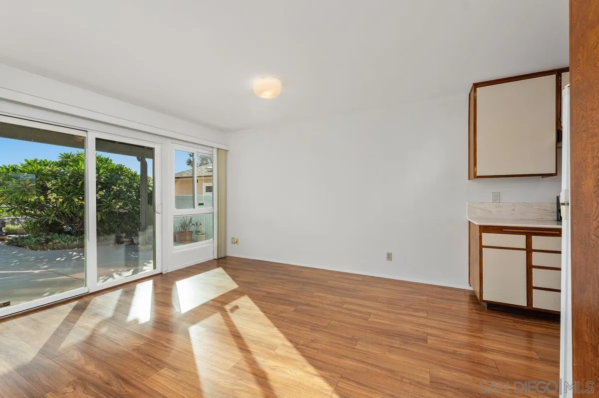 Vacant room with wood-look floors, built-in cabinetry, and sliding glass doors to a patio.
