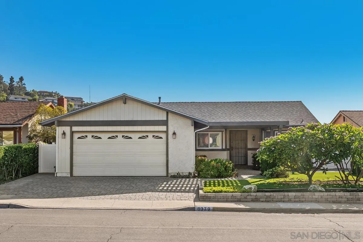 Single-story house with a two-car garage, paved driveway, and landscaped front yard.
