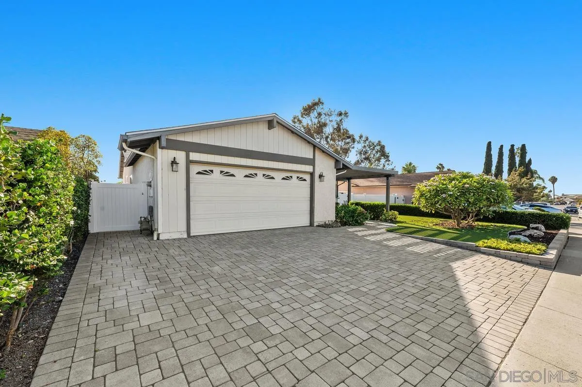 White single-story house with a wide garage, paved driveway, and landscaped front yard.