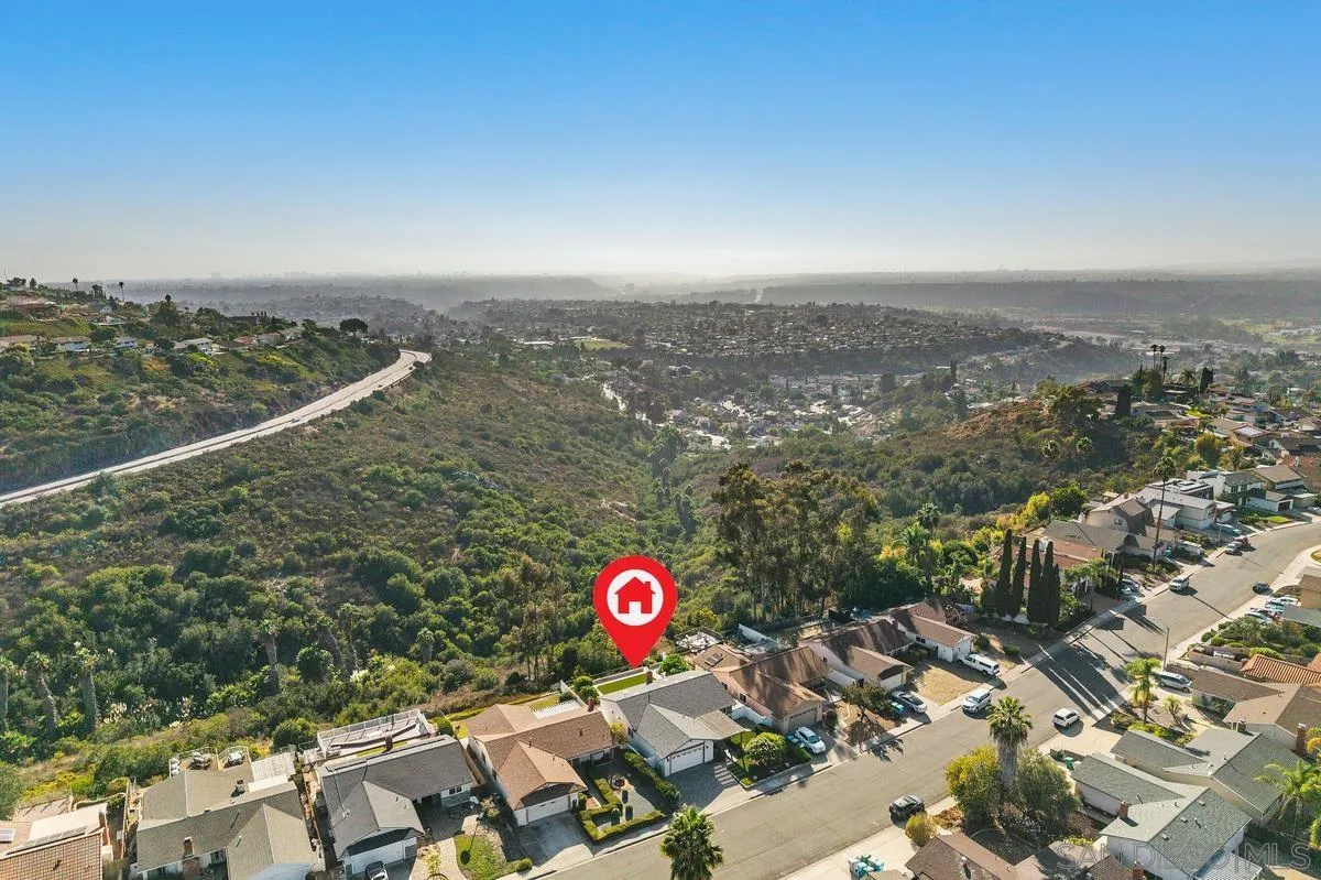 Aerial view of a home beside a green canyon, with the city stretching across the horizon.