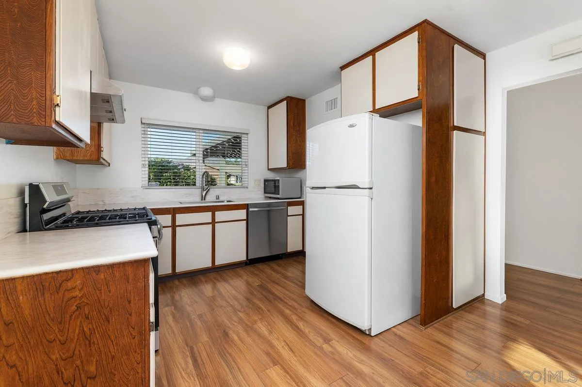 Kitchen with wood-trimmed white cabinets, a white refrigerator, and a gas range.
