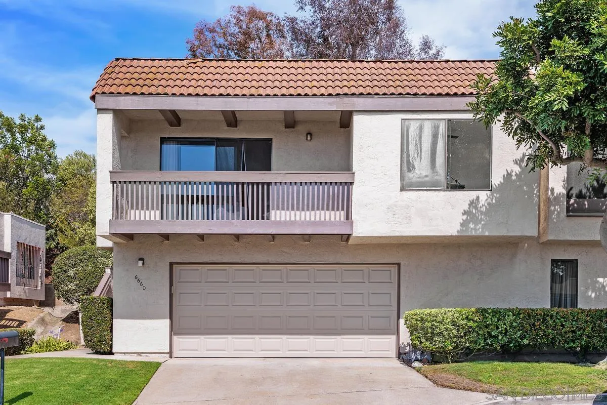 Two-story stucco home with a red tile roof, balcony, and attached double garage.