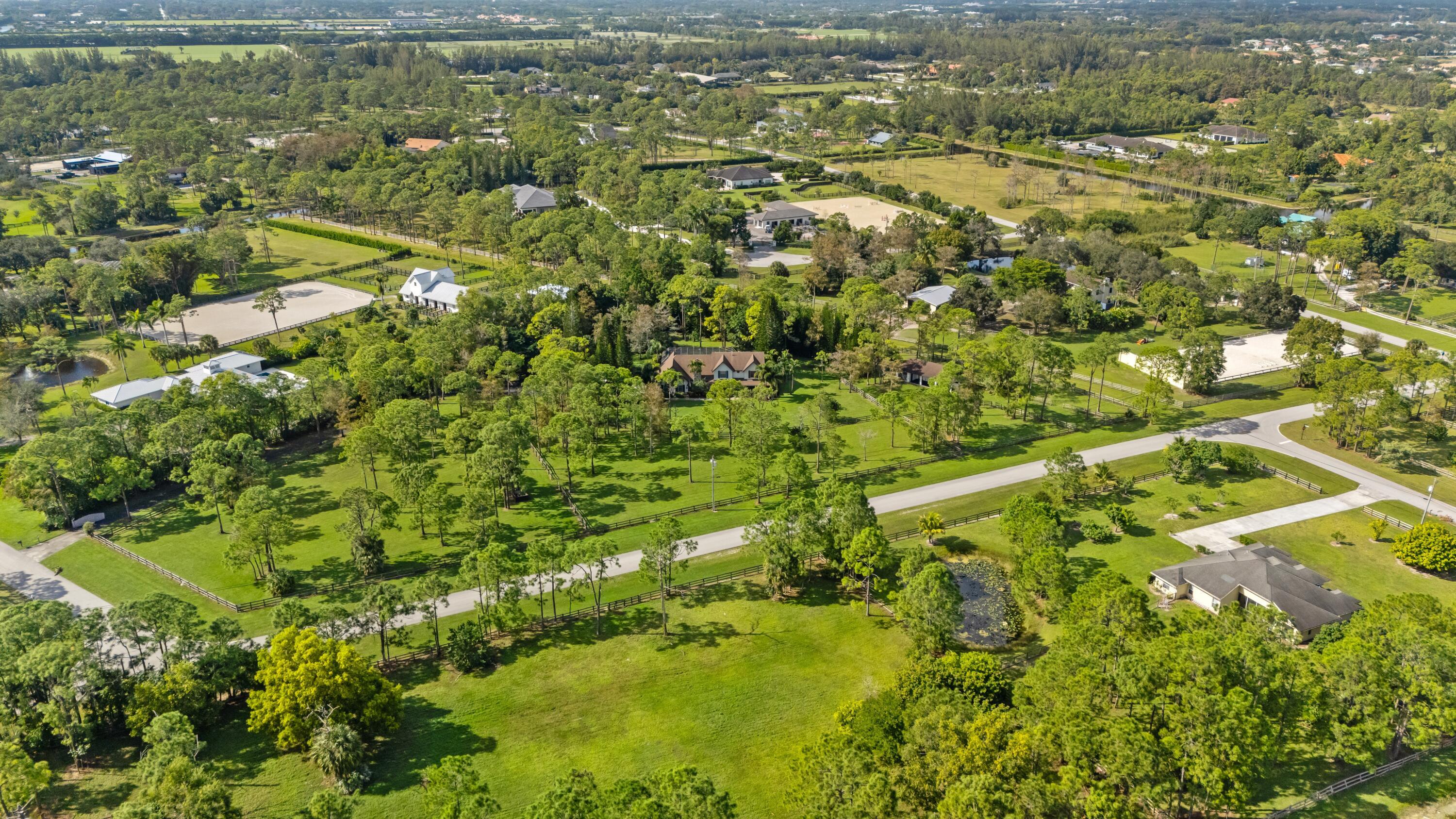 Aerial view of an equestrian property with fenced paddocks, riding arenas, and homes.