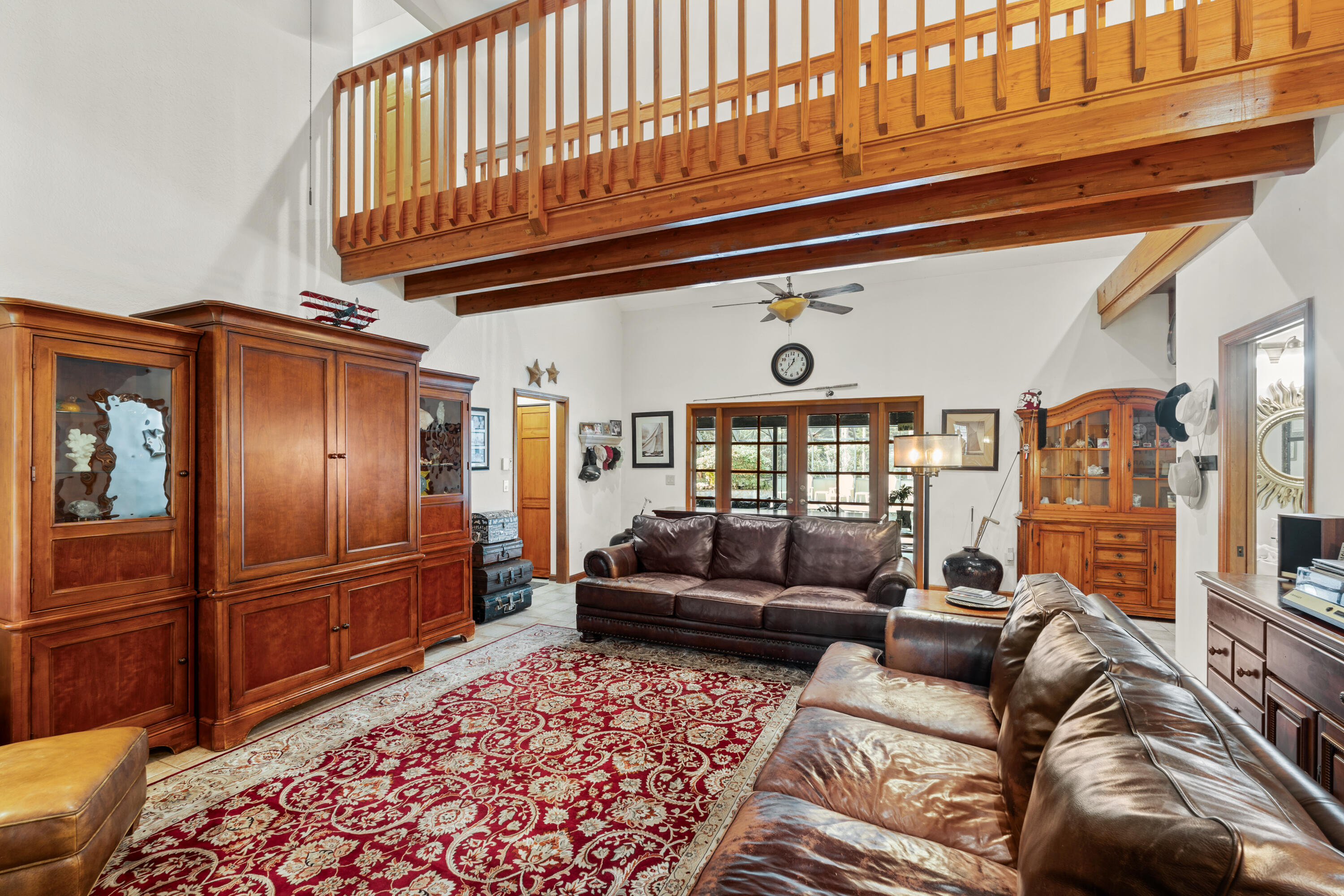 Living room with leather sofas, a red patterned rug, and a wooden mezzanine.