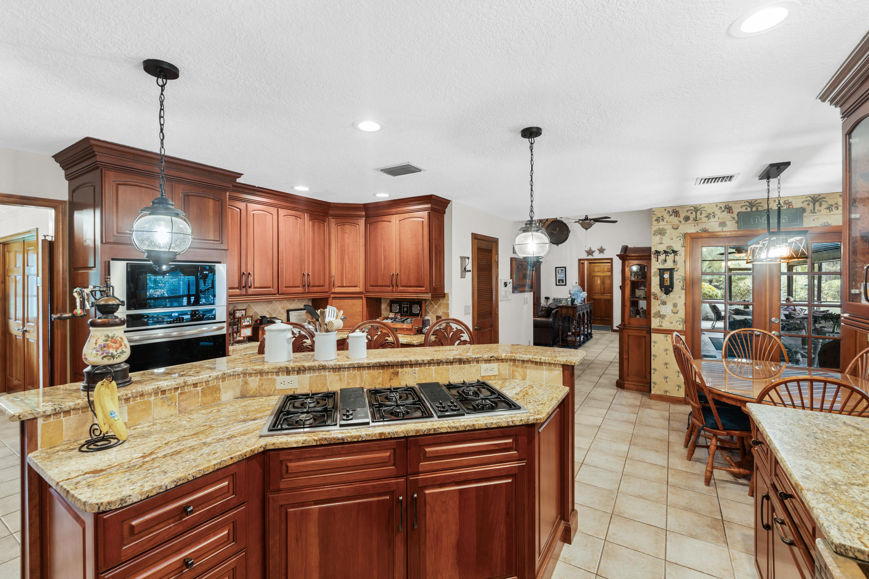 Kitchen with cherry cabinetry, granite island and cooktop, double ovens, and an adjoining dining area.