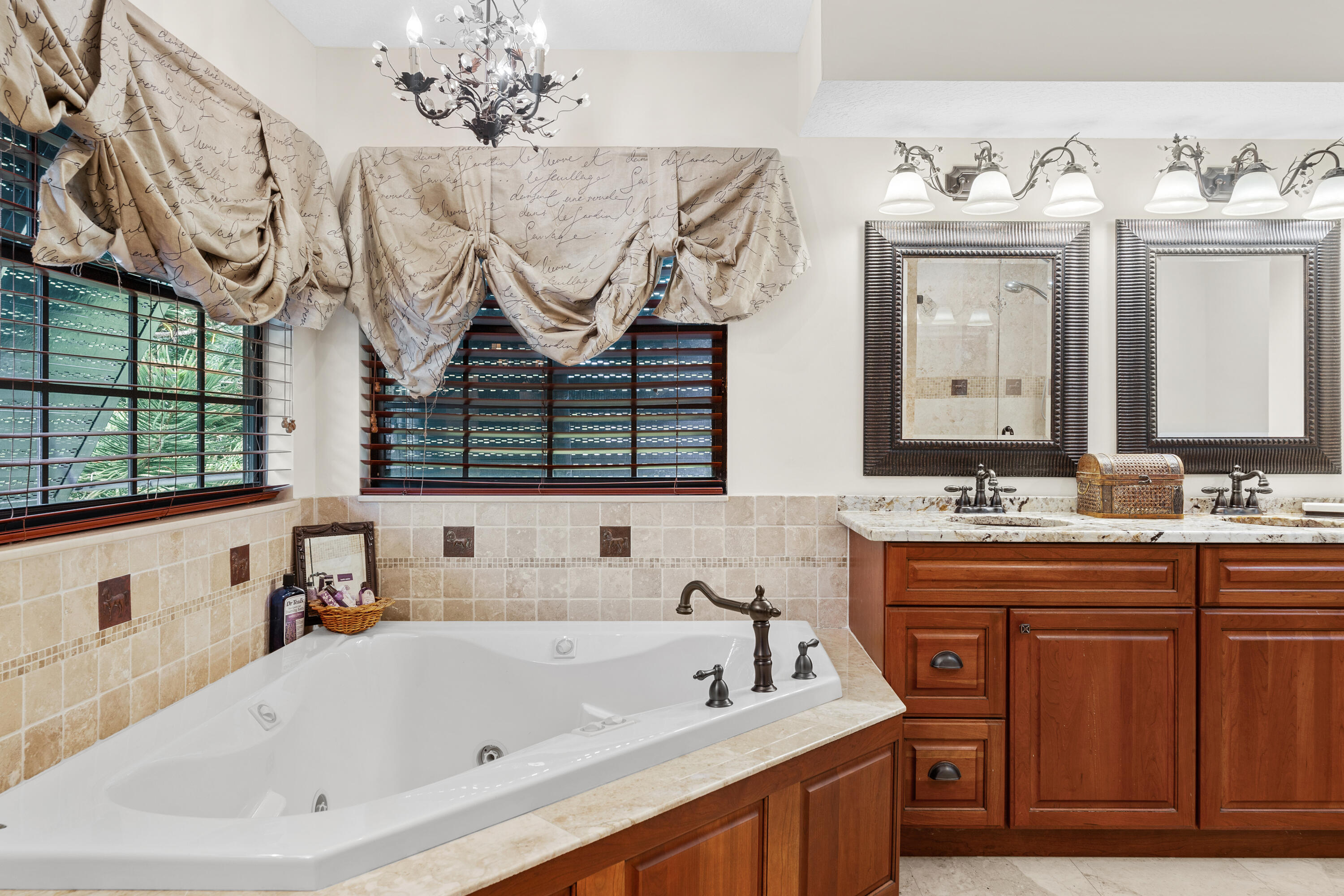 Bathroom with a corner soaking tub, wood double vanity, and draped window valances.
