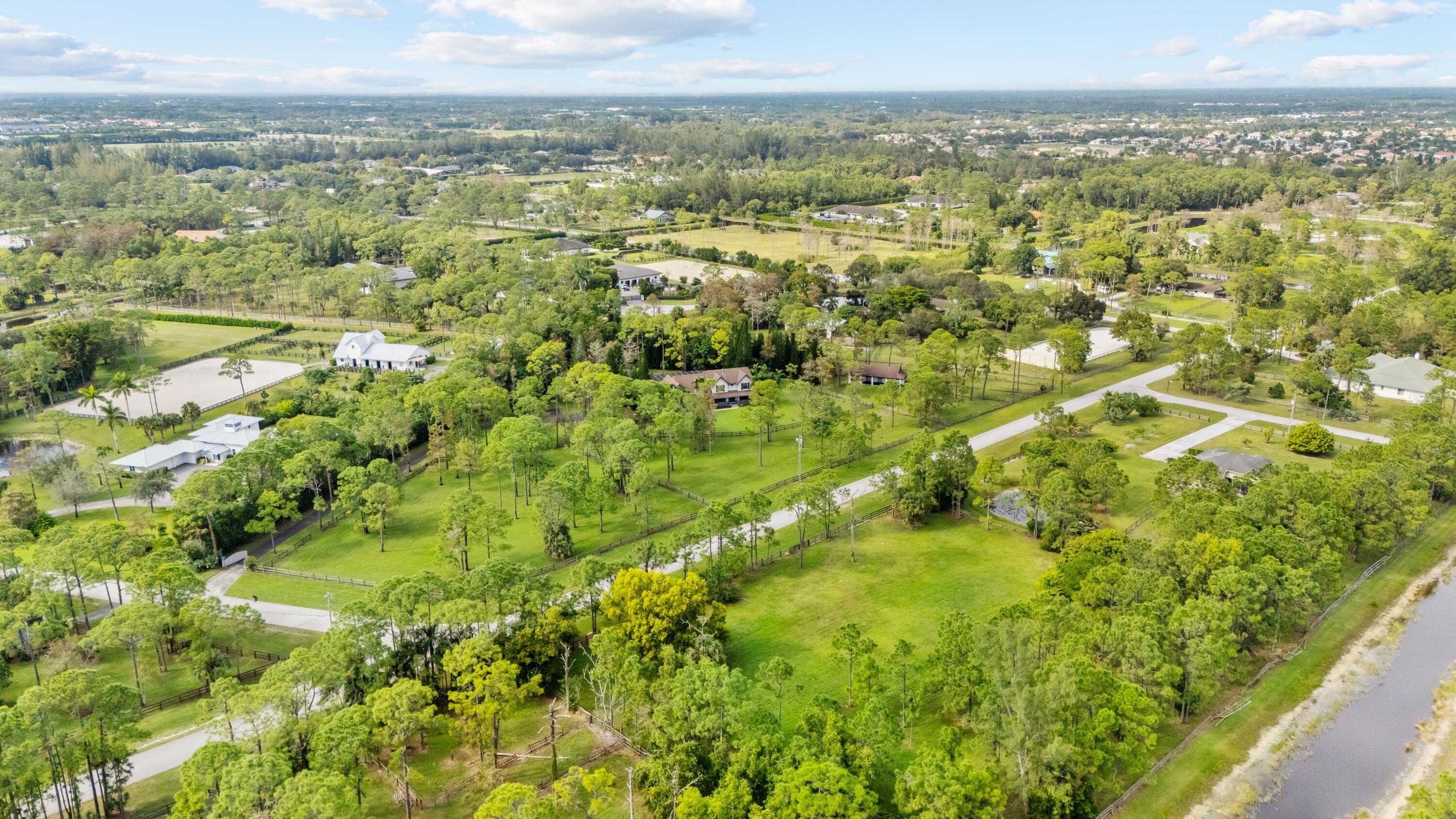 Aerial view of a wooded equestrian property with fenced paddocks and riding areas.