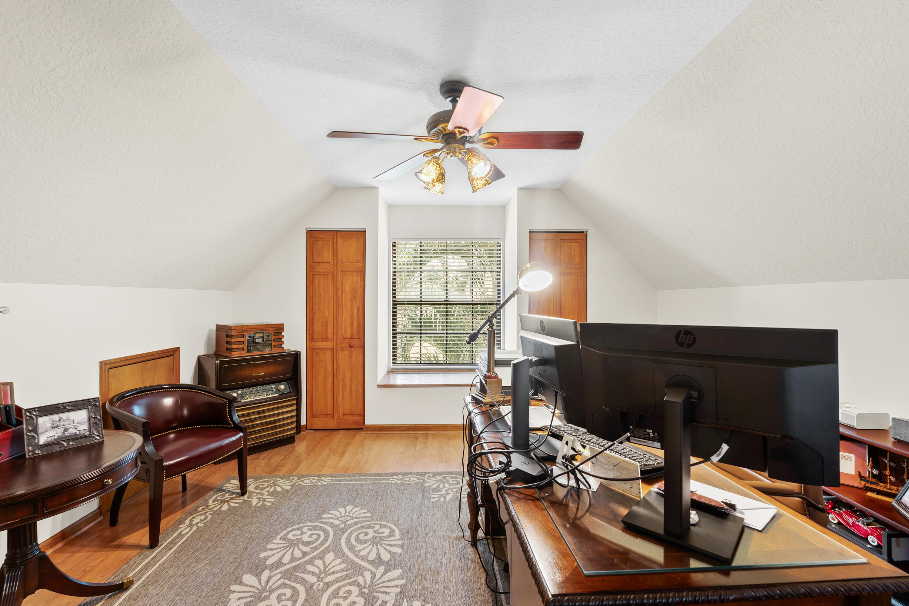 Home office with vaulted ceiling, multiple monitors, a leather chair, and a vintage stereo.