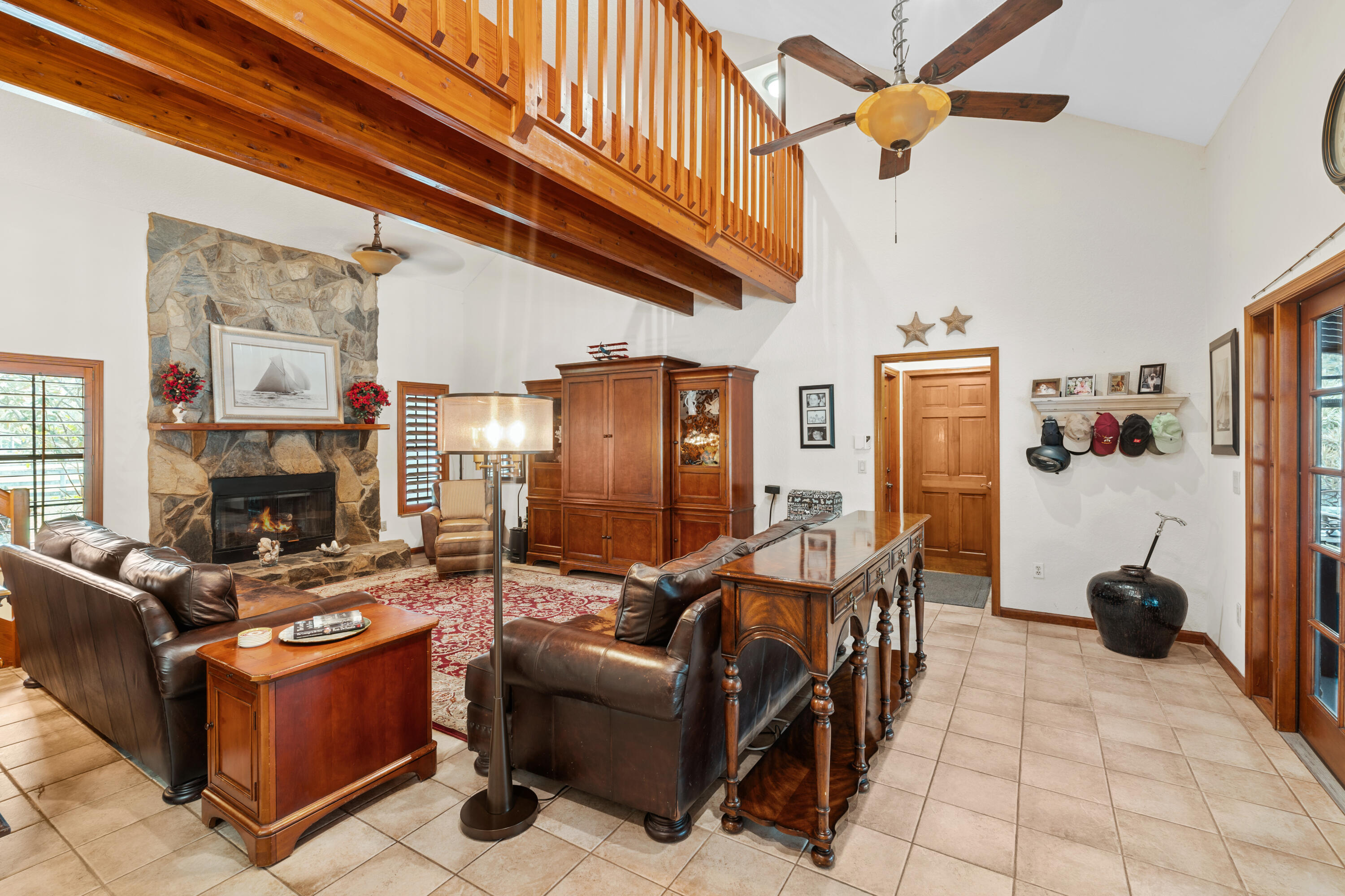 Living room with a stone fireplace, leather sofas, and a wood-railed loft.