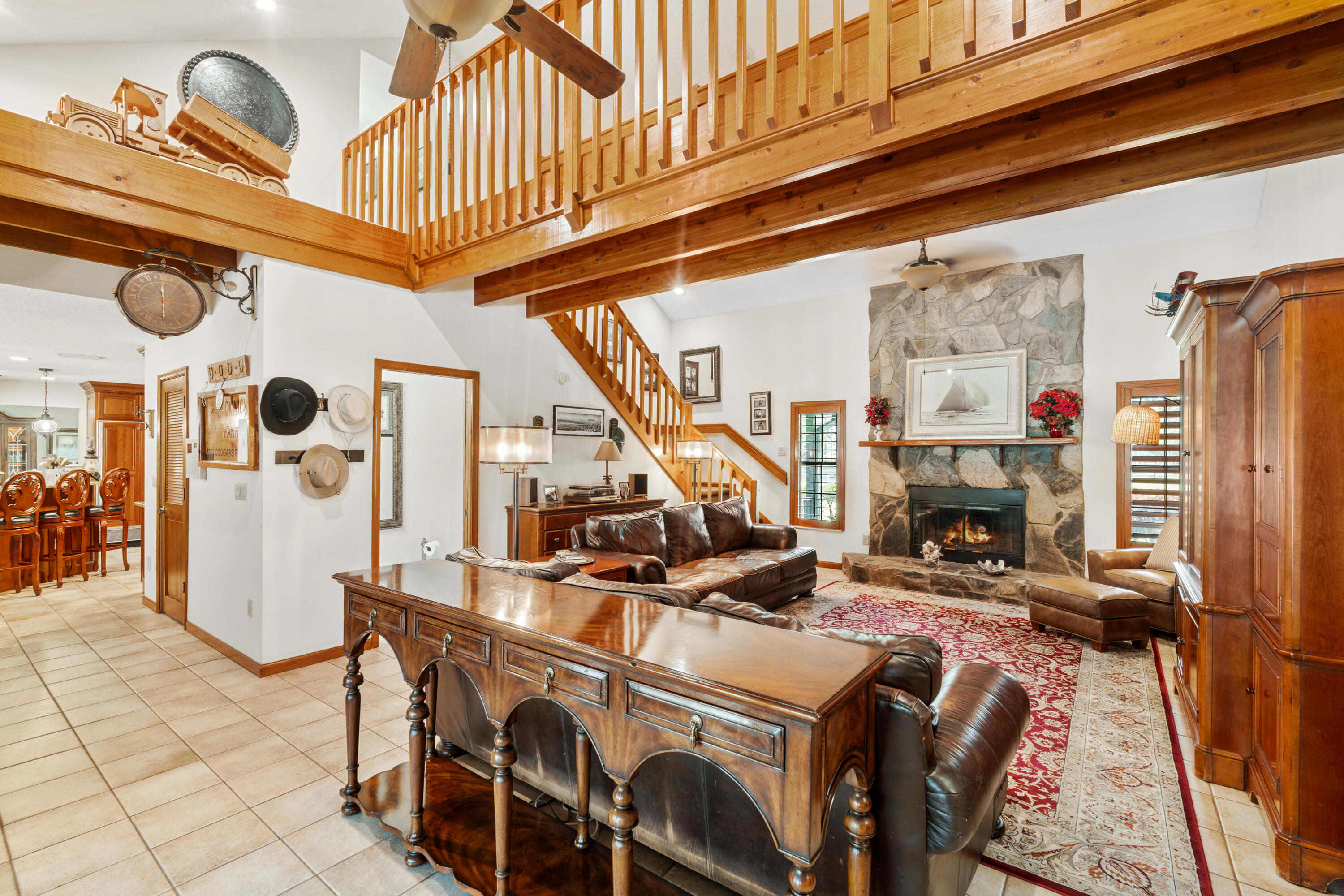 Living room with a stone fireplace, leather sofas, and a prominent wooden loft and staircase.