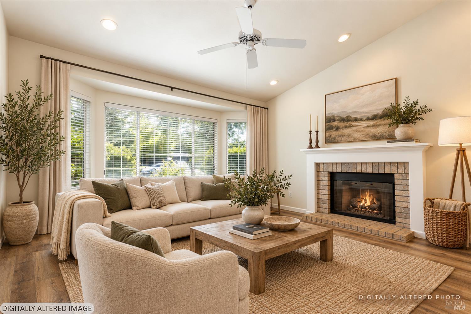 Staged living room with a brick fireplace, large windows, and neutral furnishings.