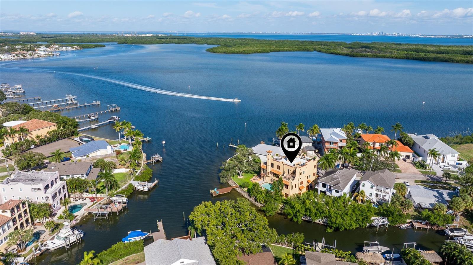 Aerial view of a tan waterfront home marked by a pin, with docks and a boat on the bayou.
