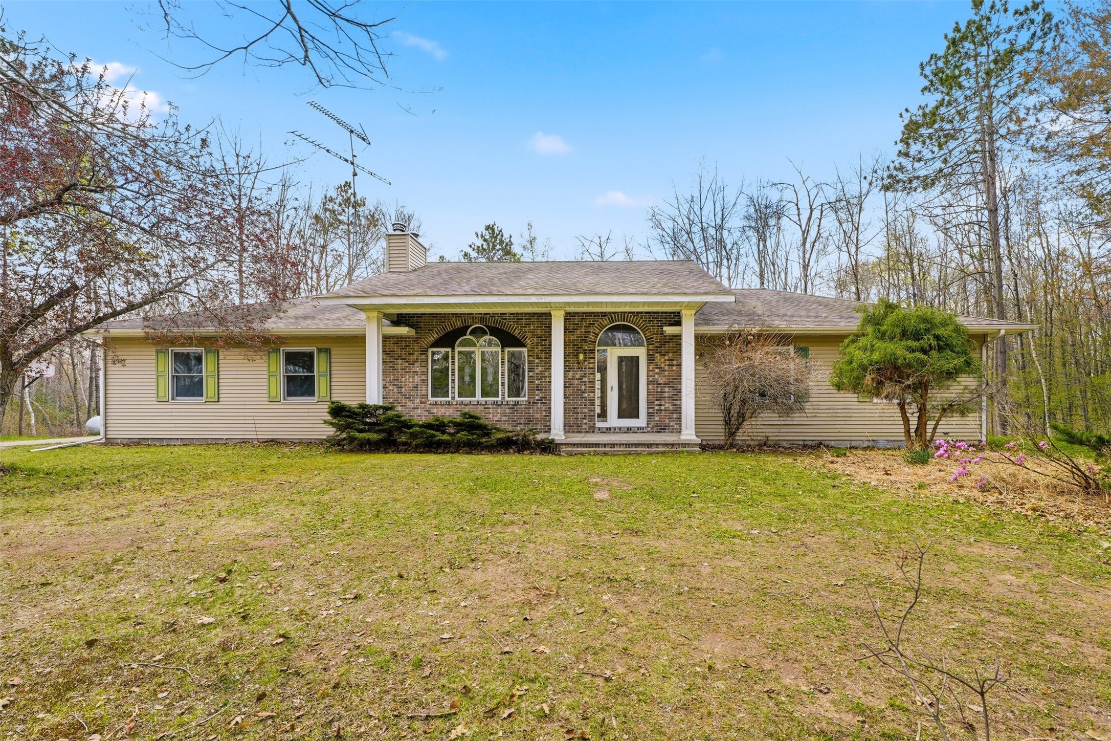 Single-story ranch home with a brick entry, arched windows, and a broad lawn.