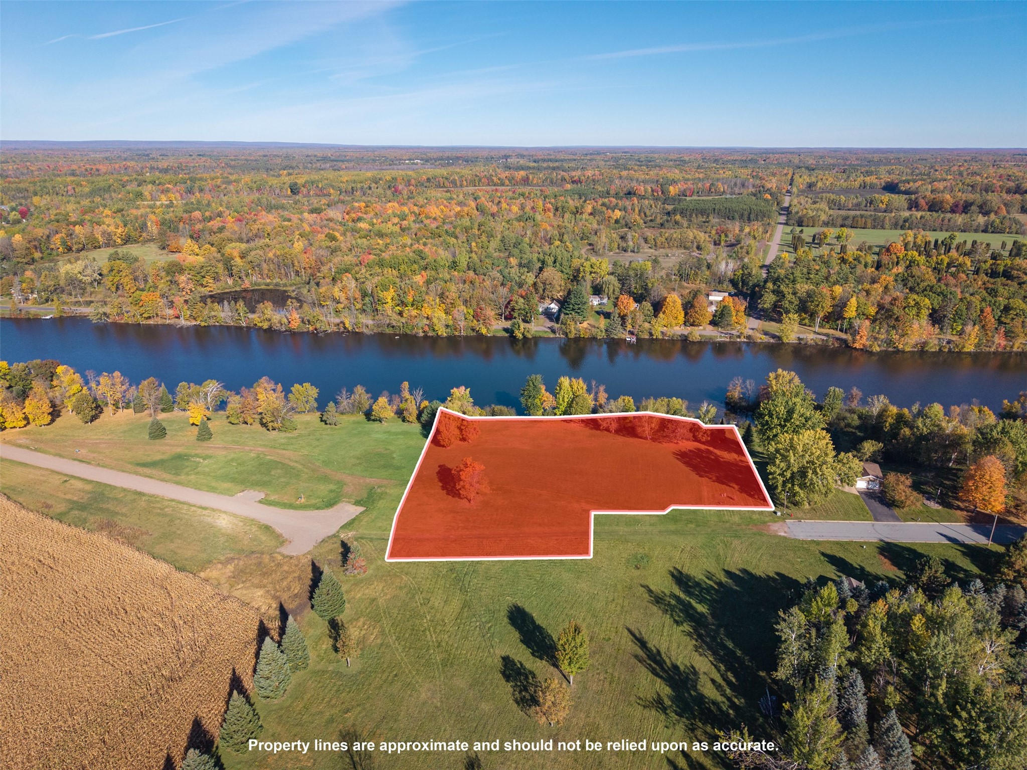 Aerial view of a red-outlined parcel beside a river, surrounded by autumn trees.