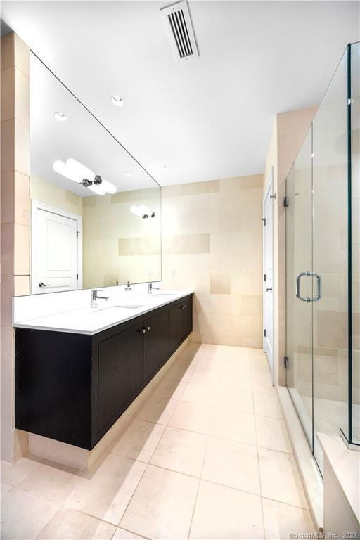 Modern bathroom with a long dark double vanity and glass-enclosed shower.