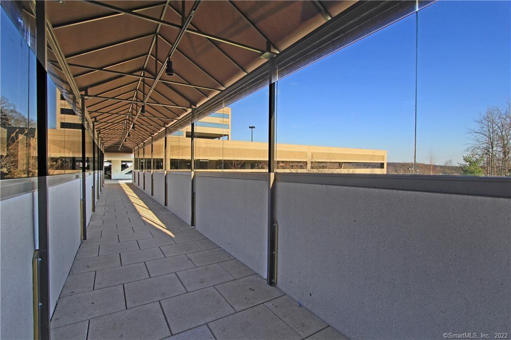Covered walkway with gray paving, concrete walls, and a geometric metal canopy.